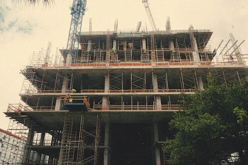 Modern construction site with cranes and workers building a multi-story building.