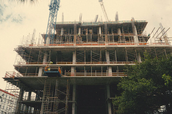 Construction workers collaborating on a new building site with cranes and scaffolding.
