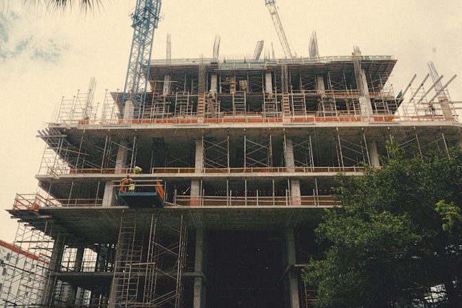 Modern construction site with cranes and workers in green safety gear.