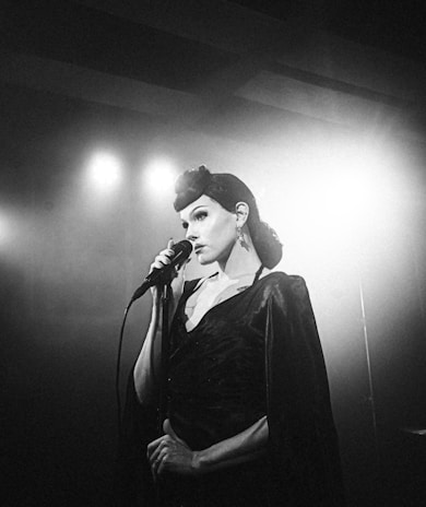 Bea Star smiling backstage, holding her microphone and wearing a stylish outfit.