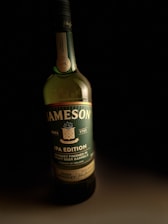 A Jameson whiskey bottle labeled as an IPA edition. The label indicates it's finished in craft beer barrels and originates from Ireland. The bottle is placed against a dark background, highlighting its green and black colors with gold accents.