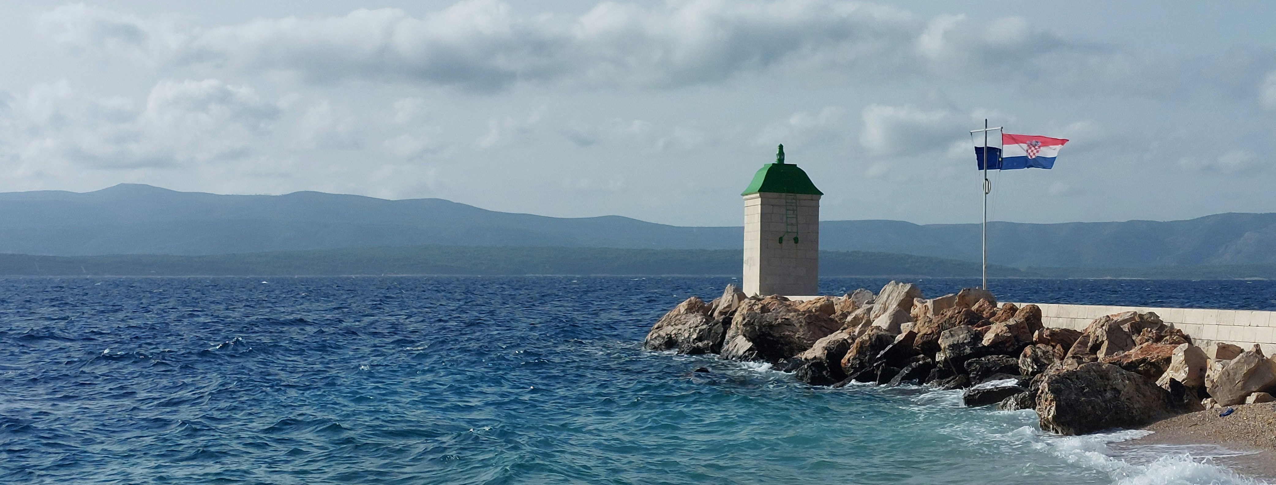 a lighthouse on a rocky shore with a flag on top