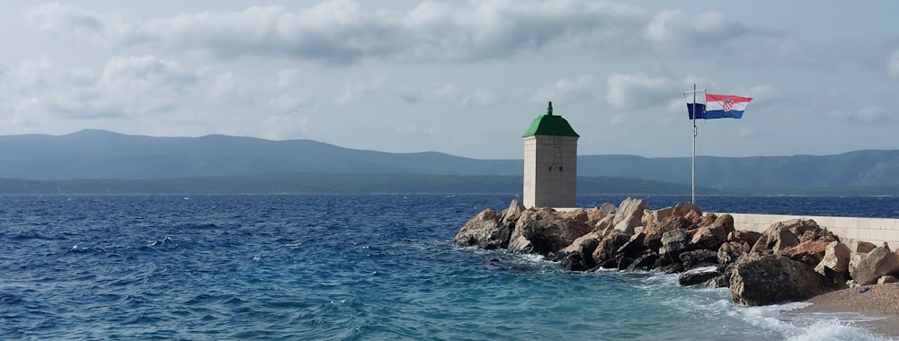 a lighthouse on a rocky shore with a flag on top