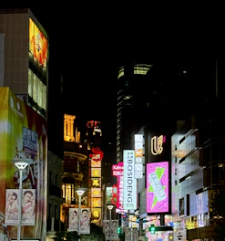 A bustling Mumbai street at night illuminated by colorful outdoor billboards.