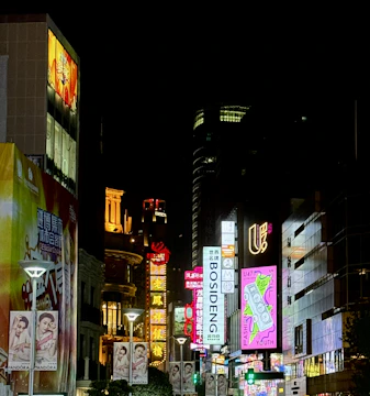 A bustling Mumbai street at night illuminated by colorful outdoor billboards.