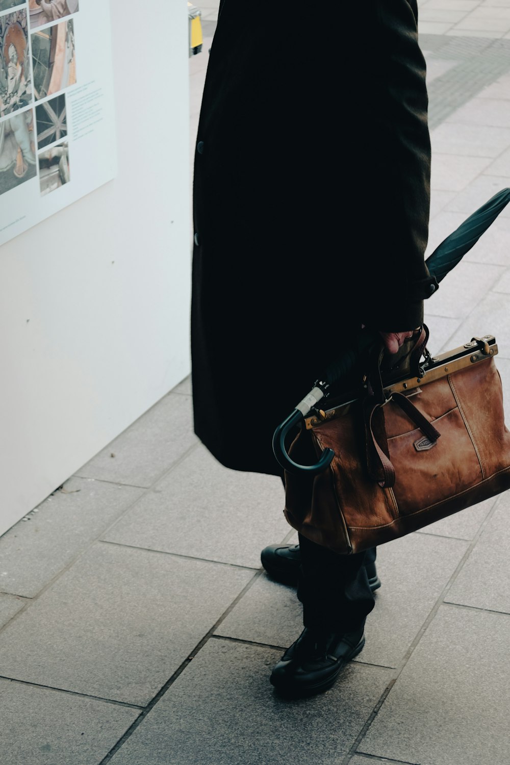 a person in a black coat carrying a brown bag