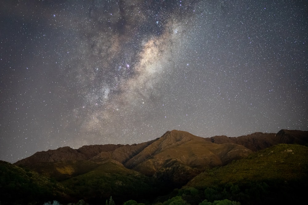 the night sky with stars above a mountain range