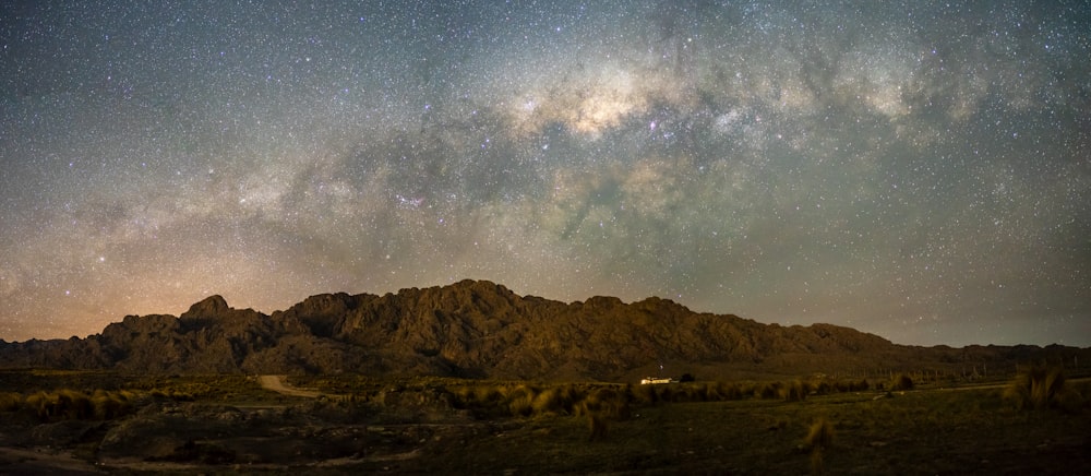 the night sky with stars above a mountain range