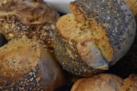 Several pieces of rustic bread covered with a mix of seeds, including poppy and sesame. The bread has a golden-brown crust and a textured surface, suggesting a hearty and crunchy exterior.