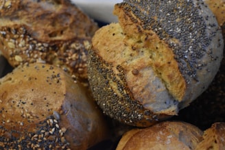Several pieces of rustic bread covered with a mix of seeds, including poppy and sesame. The bread has a golden-brown crust and a textured surface, suggesting a hearty and crunchy exterior.