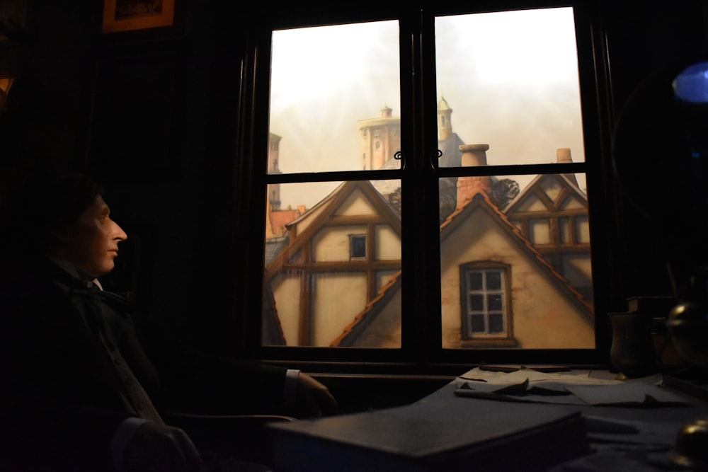 a person looking out a window at a house