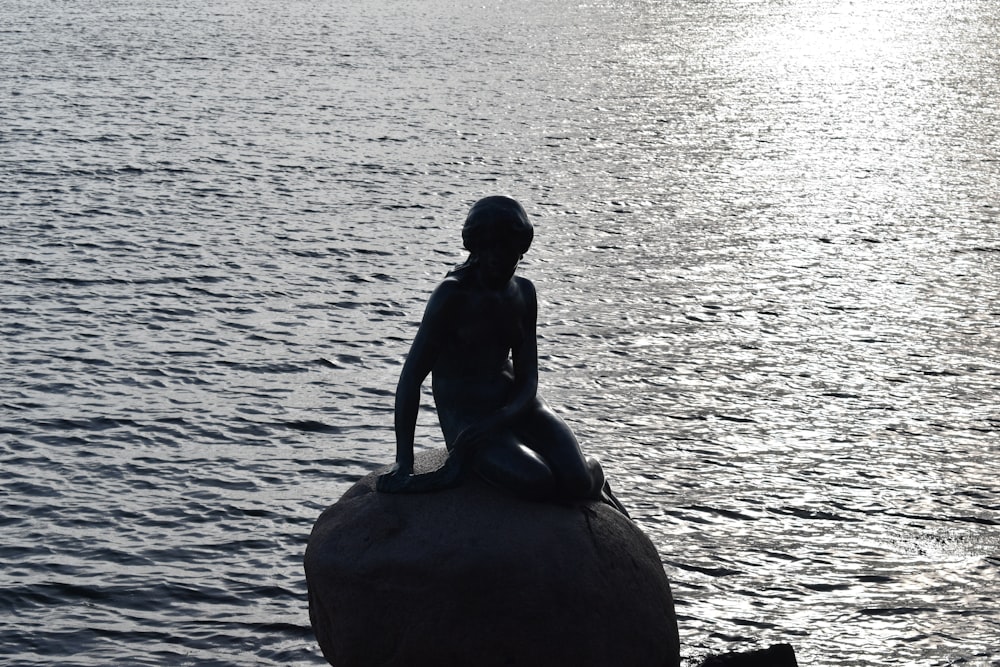 a statue of a person sitting on top of a rock