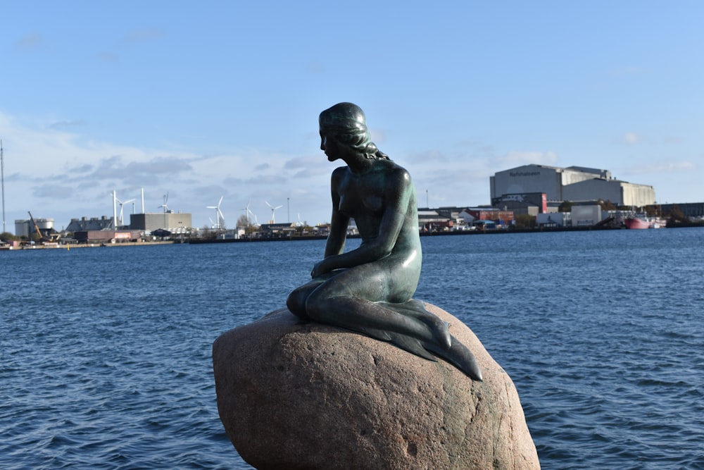 a statue of a mermaid sitting on top of a rock