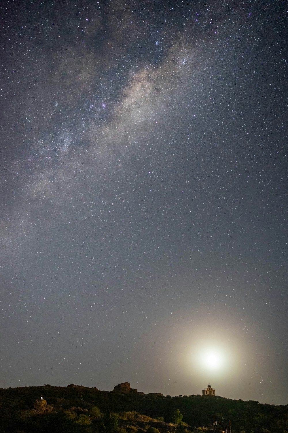 the night sky with the stars and the moon in the distance