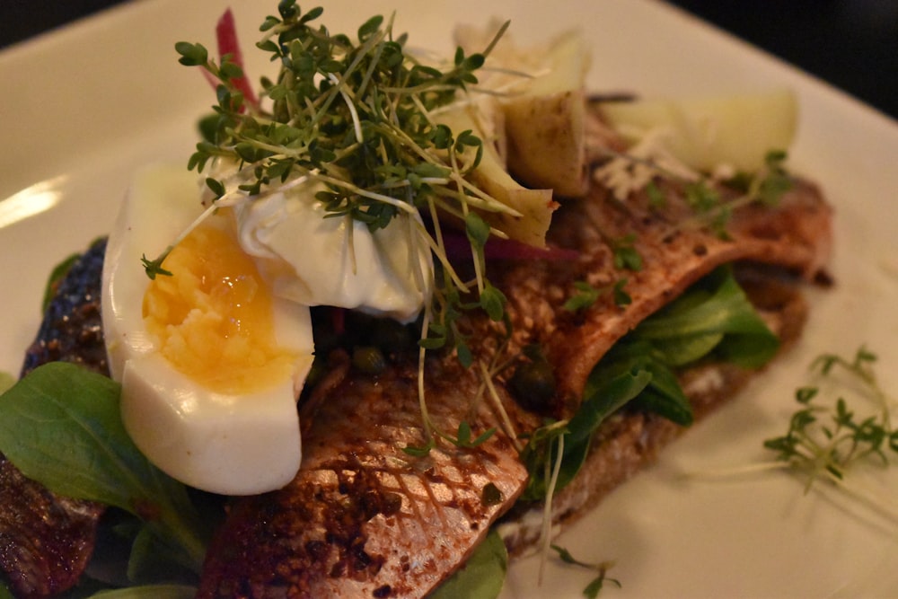 a white plate topped with fish and an egg