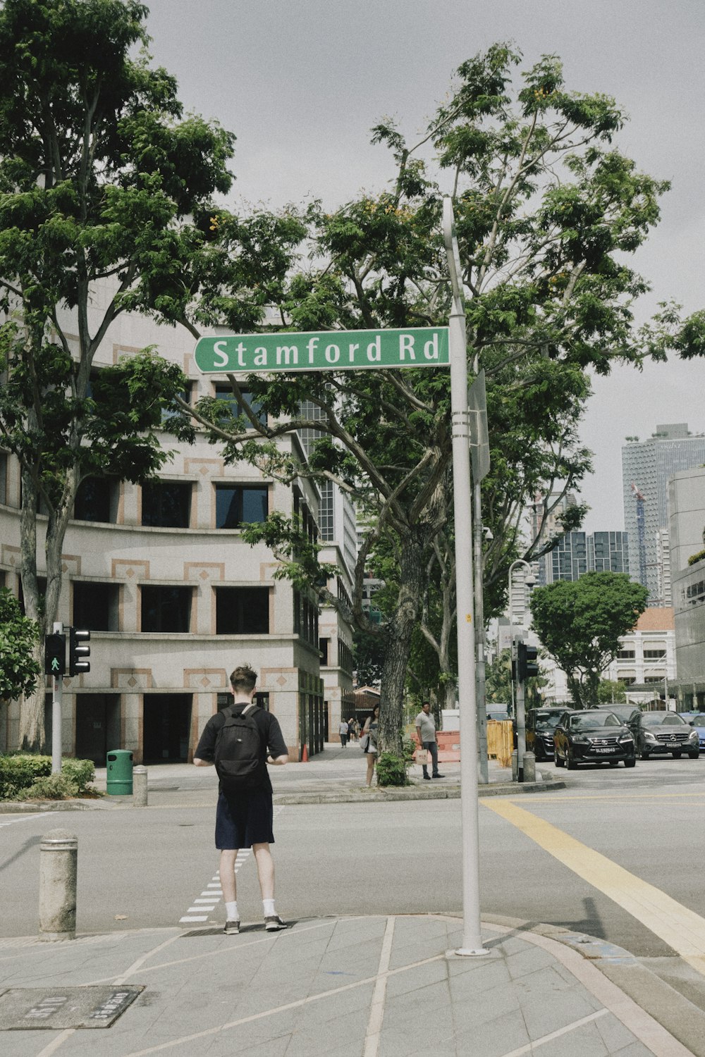 a man standing on a street corner under a street sign