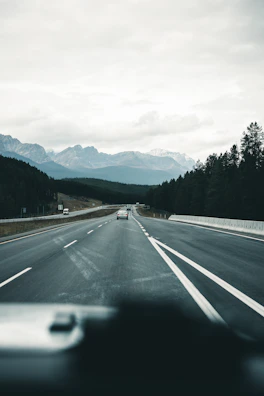 The open road stretching ahead with mountains in the distance, viewed from a van’s front windshield