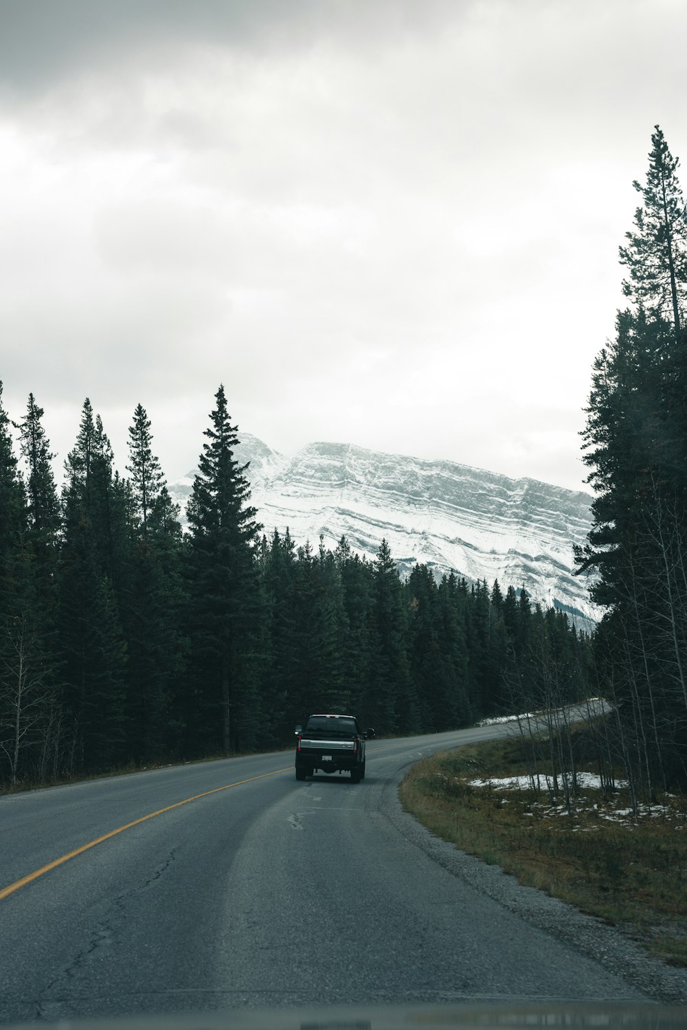 a car driving down a road with a mountain in the background