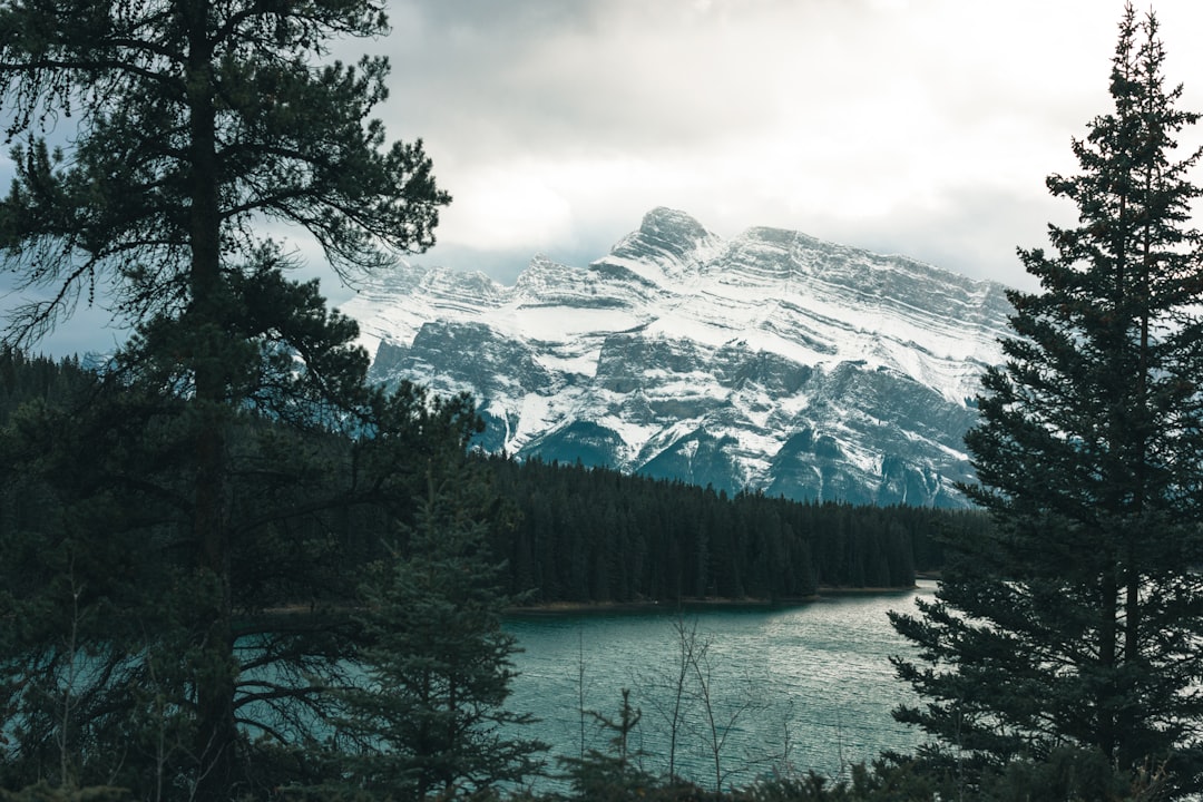 a snow covered mountain with a lake in the foreground, The road through the great Canadian rockies