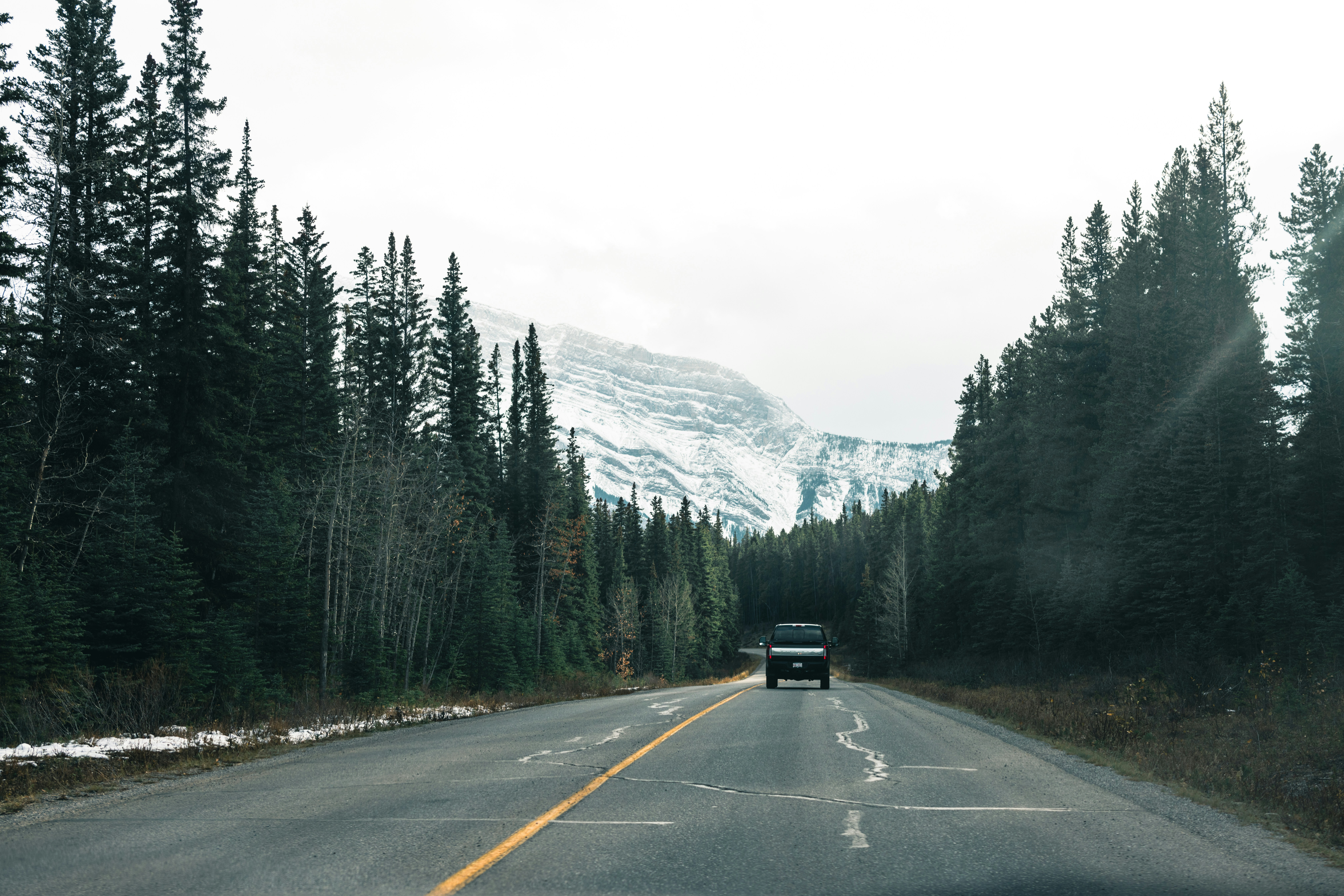 a car driving down a road with a mountain in the background