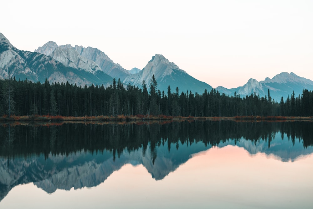 a mountain range is reflected in the still water of a lake