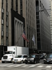 a large truck driving down a street next to tall buildings