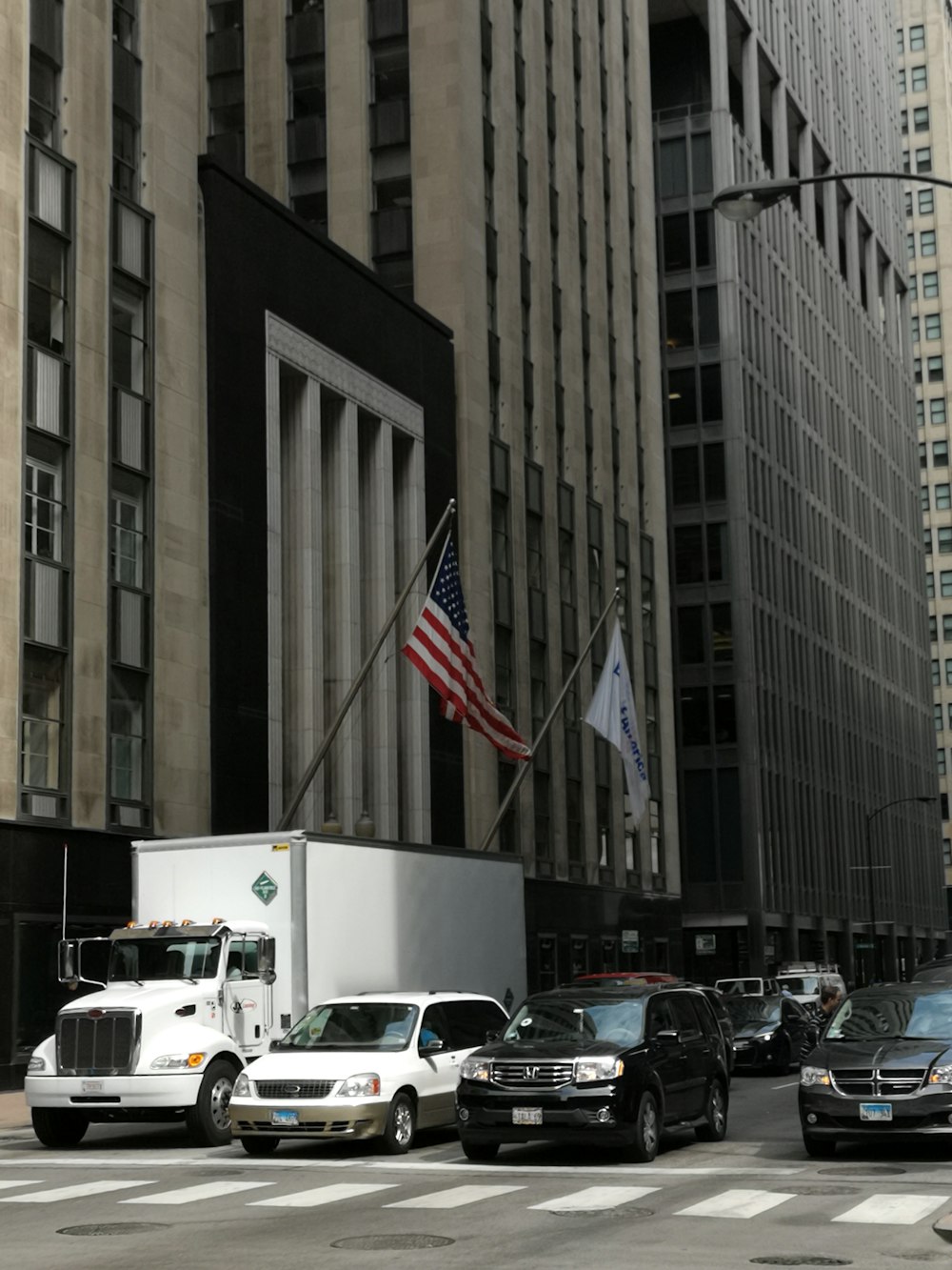 高層ビルの横の道を走る大型トラック