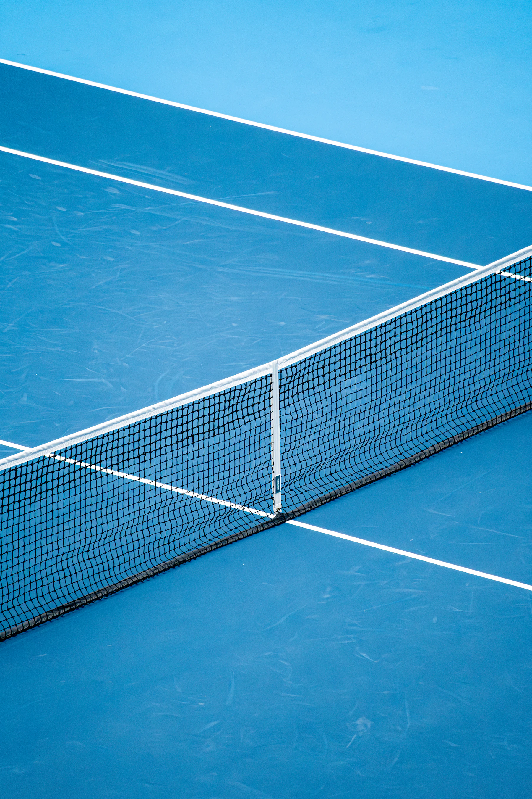 A net and its white center strap stretched across an empty blue hard court
