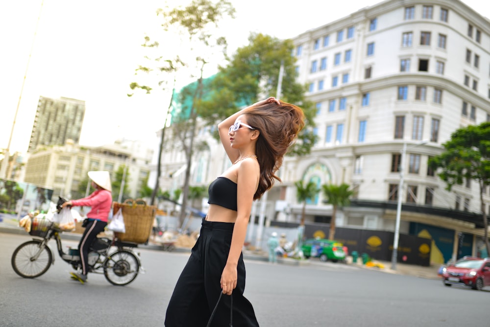 a woman in a black dress is walking down the street