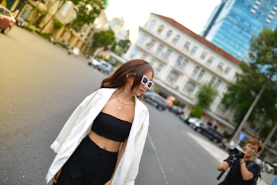 A candid shot of a woman walking through an urban street wearing layered, stylish clothes in muted tones.