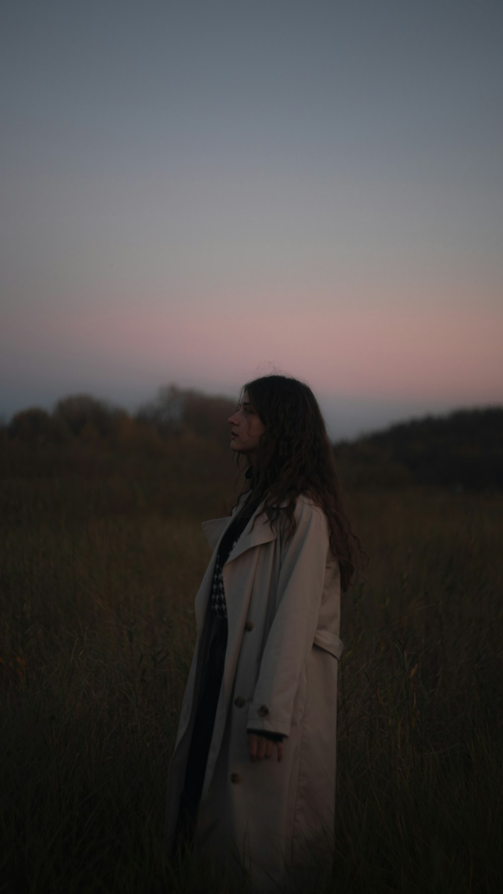 a woman standing in a field at sunset