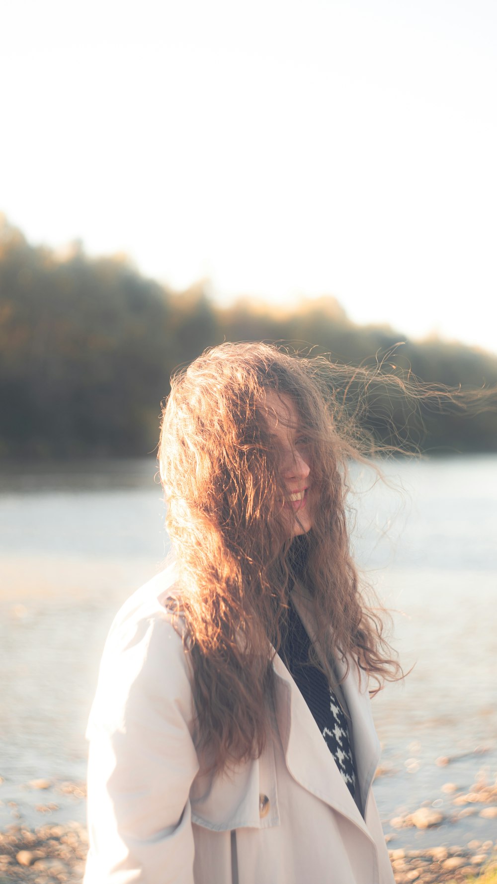 a woman with long hair standing next to a body of water