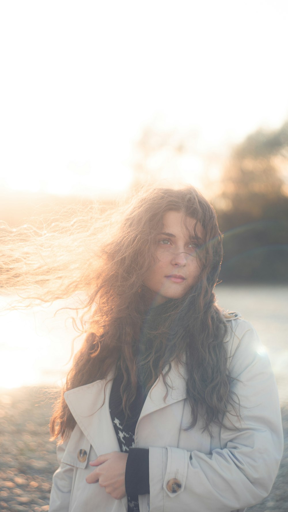 a woman standing on a beach with her hair blowing in the wind