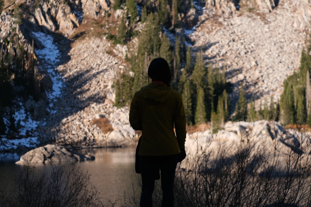 a person standing in front of a mountain lake