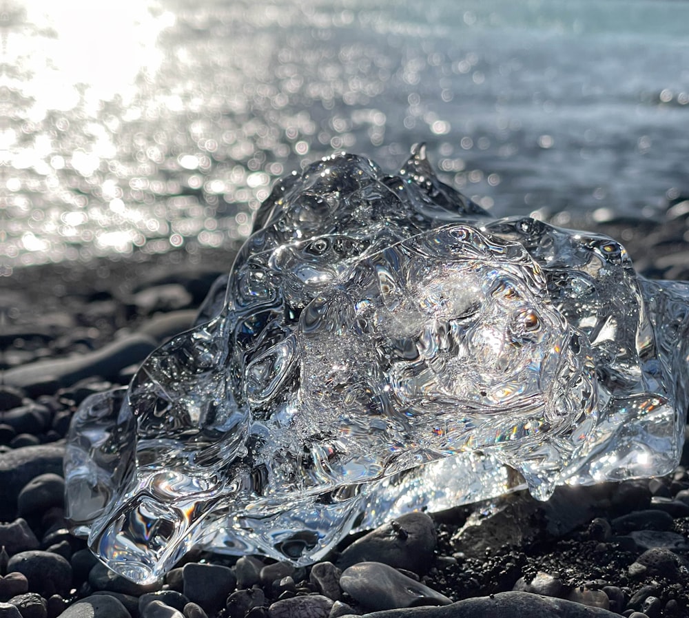 a piece of ice sitting on top of a rocky beach