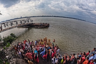 A group of volunteers warmly assisting pilgrims at the Ganga Sagar mela under a calm blue sky.