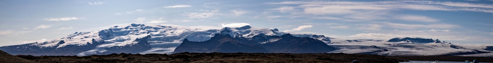 a snow covered mountain range under a partly cloudy sky