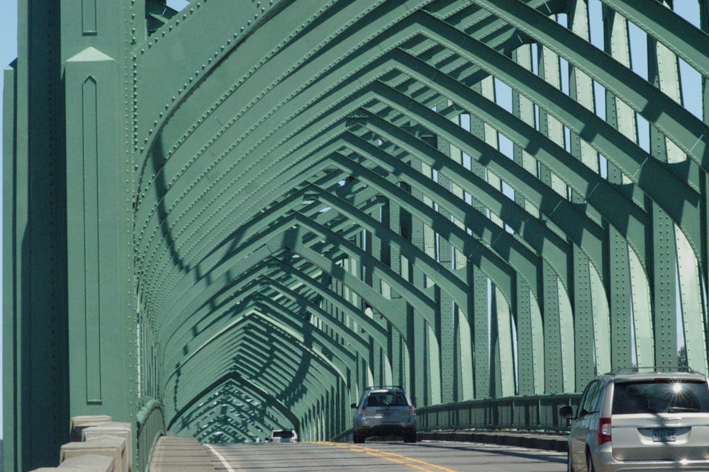 a car driving over a bridge with a green metal structure