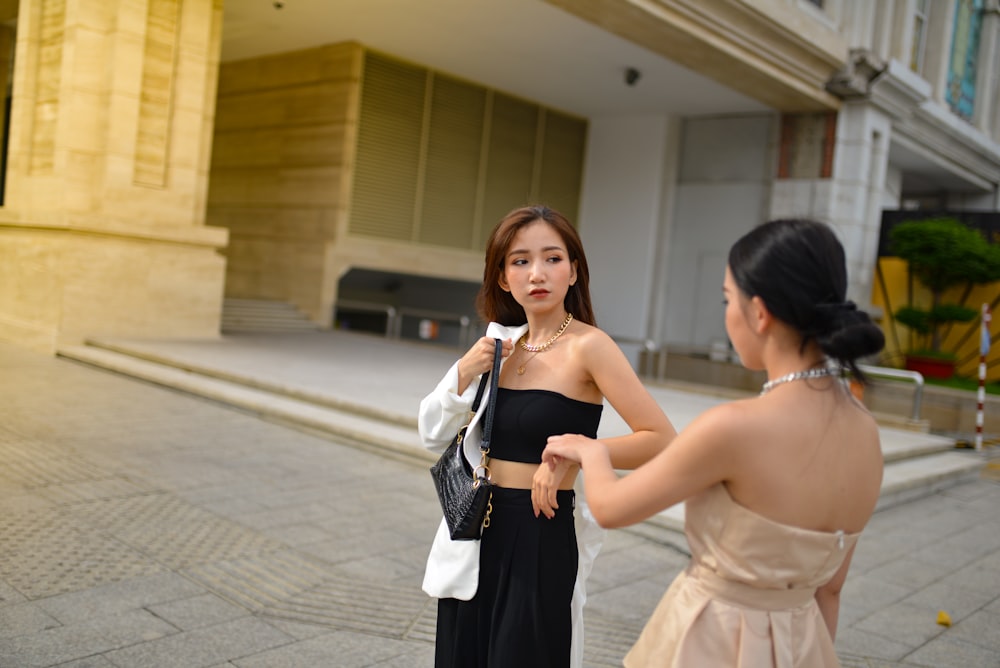 a woman standing next to a woman in a black dress