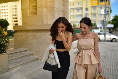 two young women walking down a sidewalk next to each other