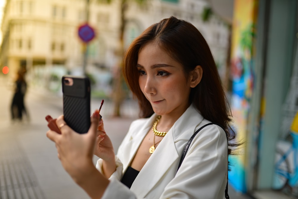a woman in a white suit holding a cell phone