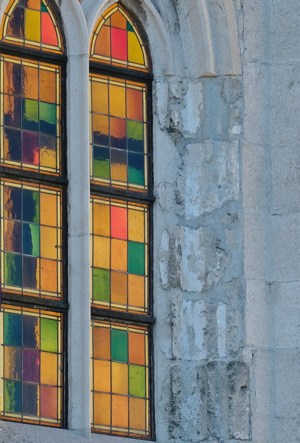 Zwei Buntglasfenster in einem Steingebäude