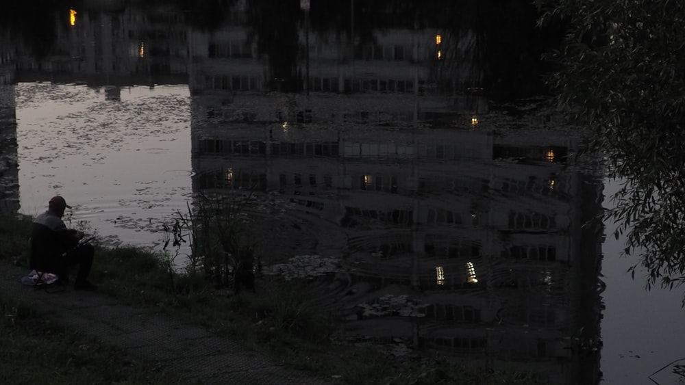 a person sitting on a bench next to a body of water