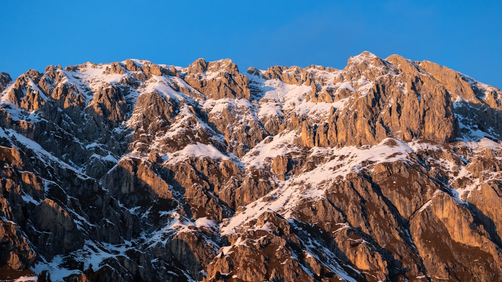 a large mountain covered in snow under a blue sky