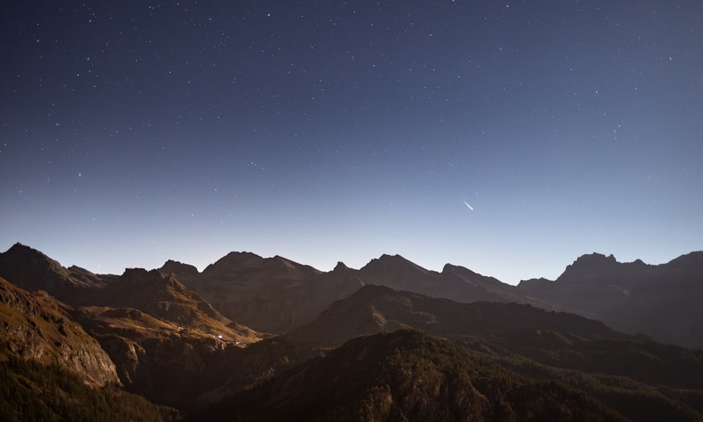 a view of a mountain range at night with stars in the sky