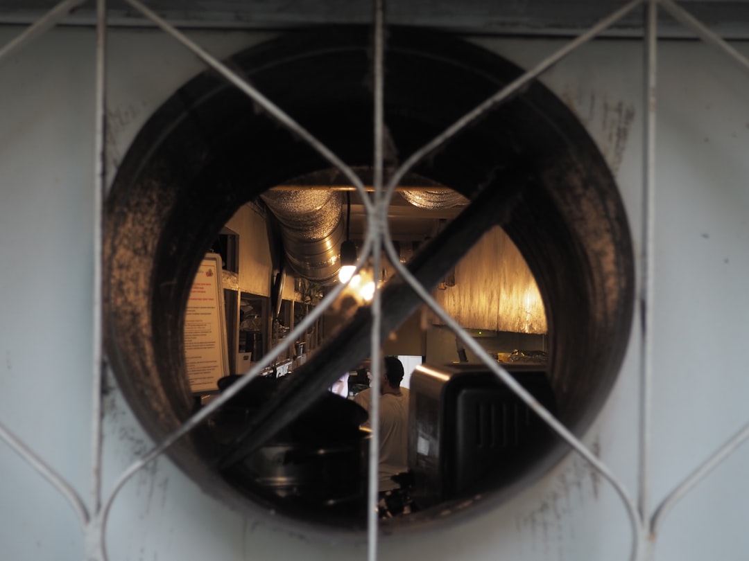 a view of a kitchen through a wire fence,
