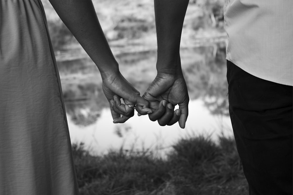 a black and white photo of two people holding hands