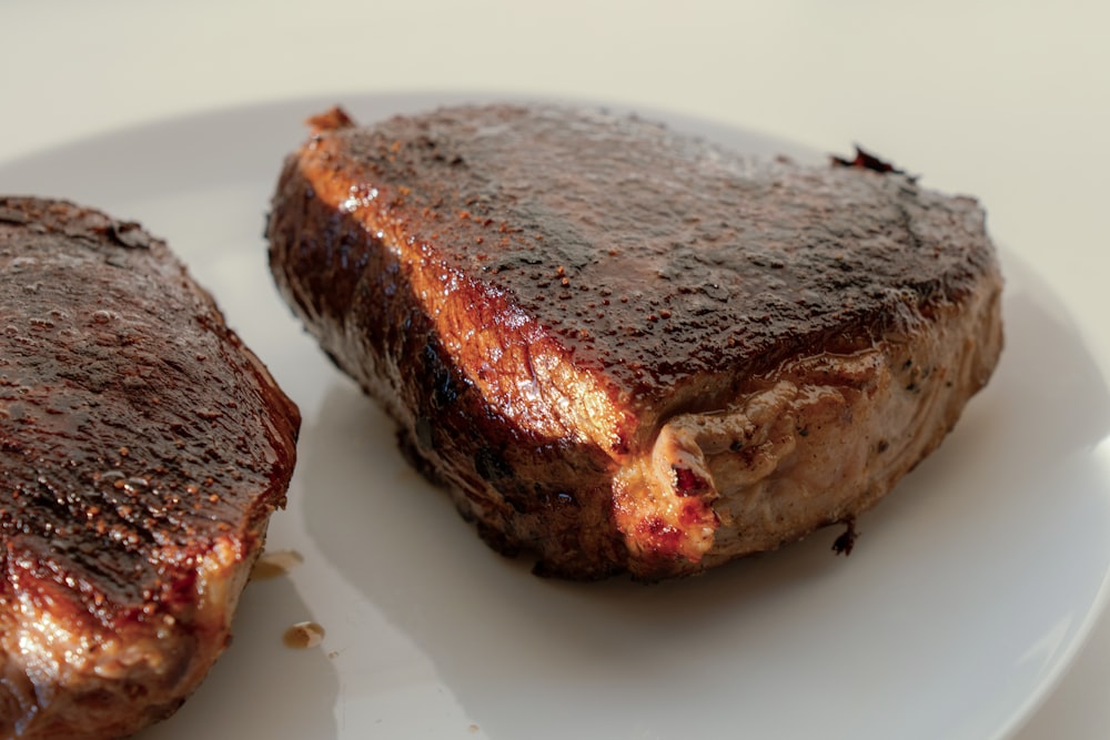 two pieces of steak on a white plate