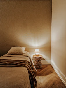 Softly lit minimalist bedroom corner with blush pink accents and warm beige textiles creating a serene, inviting vibe.