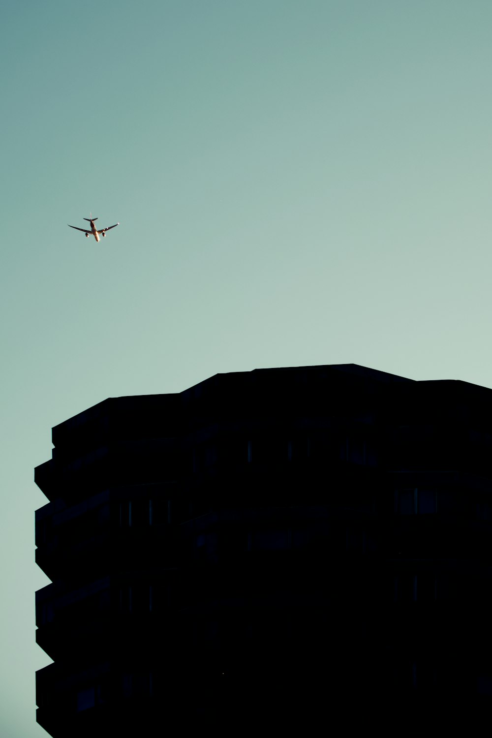 an airplane flying in the sky over a building